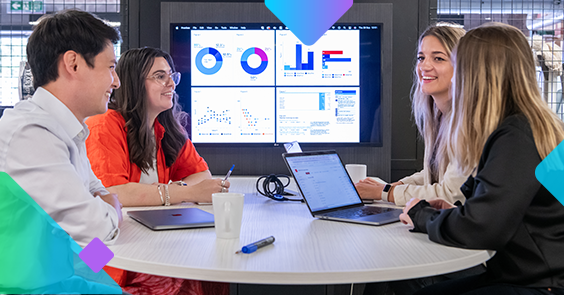 four people sitting around a table with a screen of graphs