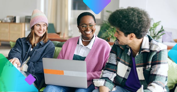 three young people smiling on a couch with a laptop