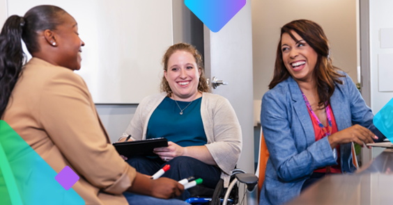 women sitting smiling and laughing infront of a white board